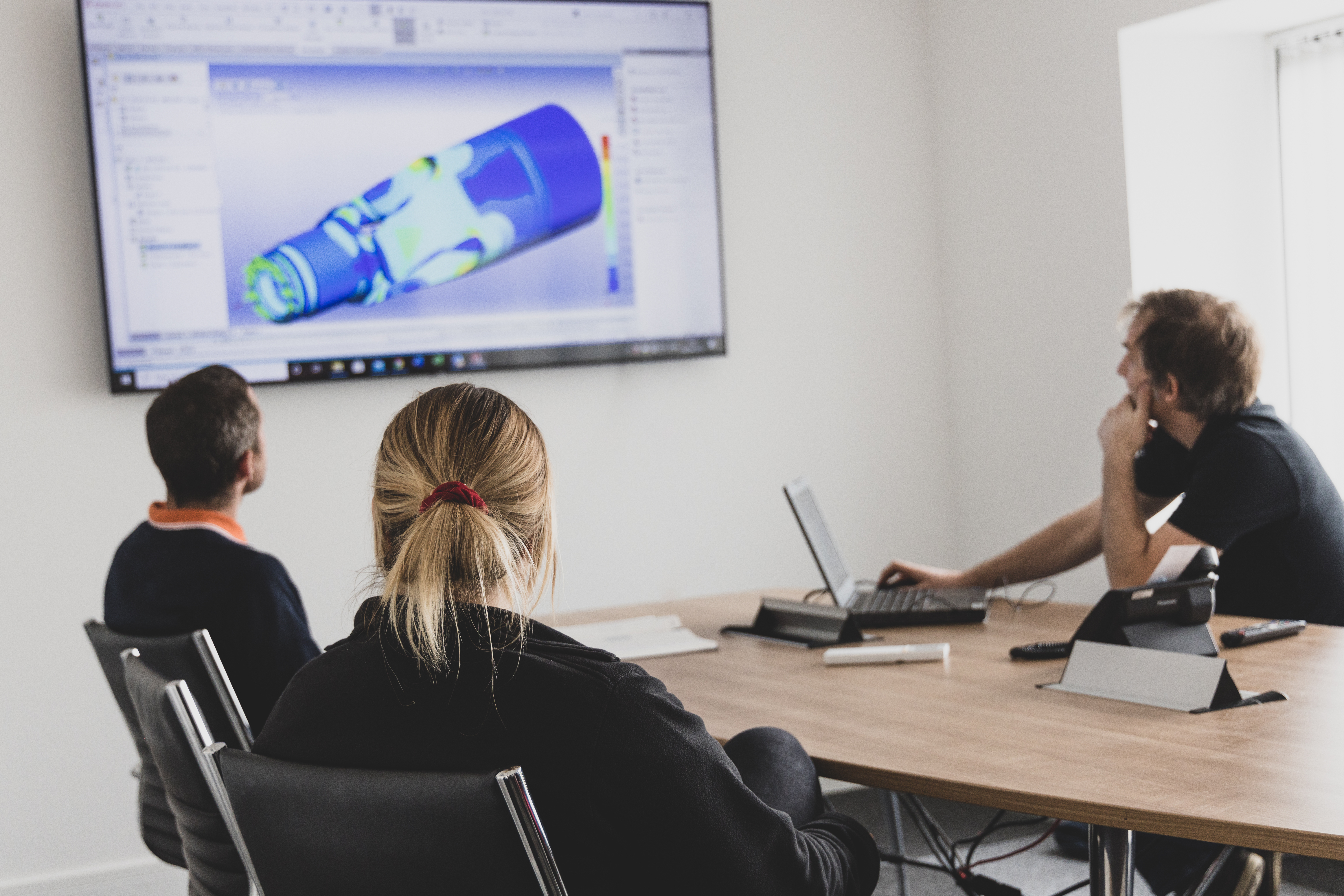 Three People Sat Around A Meeting Room Table